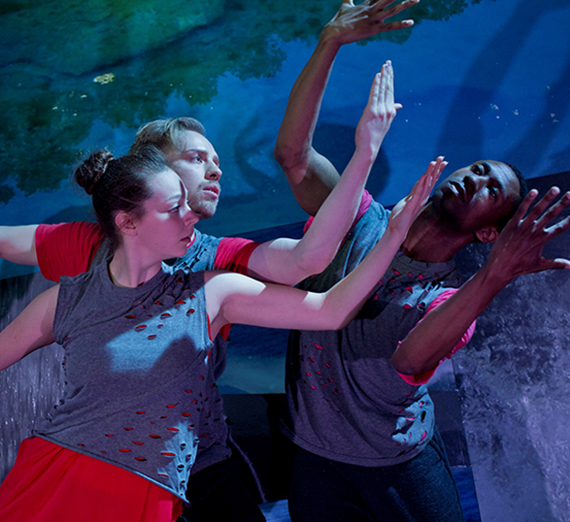 Three dancers hold their arms high