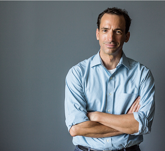 Author Paul Tough standing with his arms crossed