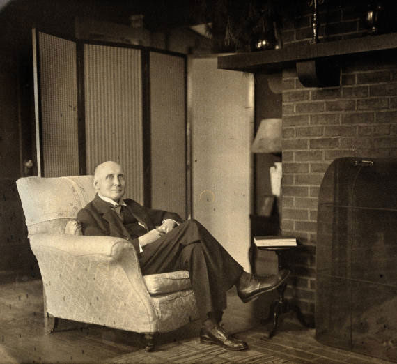 Alfred North Whitehead sitting in a chair, looking at the camera