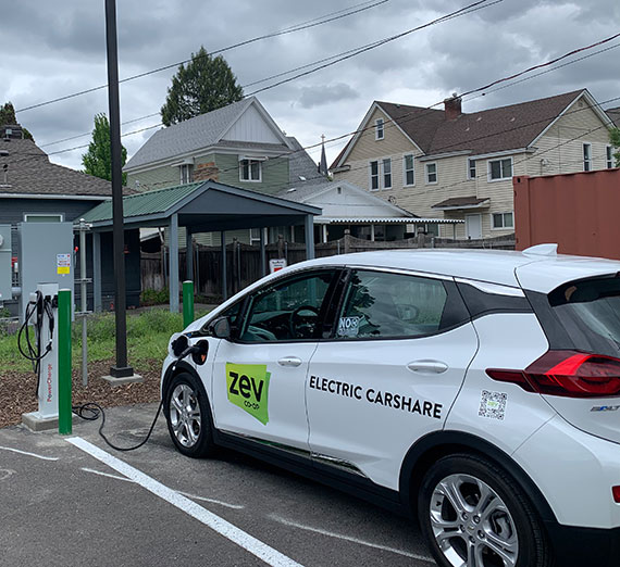 A small white car plugged into an electricity station