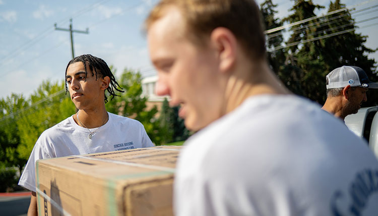 Two men carry a box 