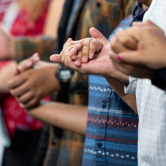 Photo zoomed in on a line of people holding hands together.