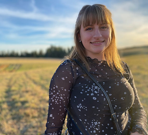Student Mia Foster looks at camera while standing in a field