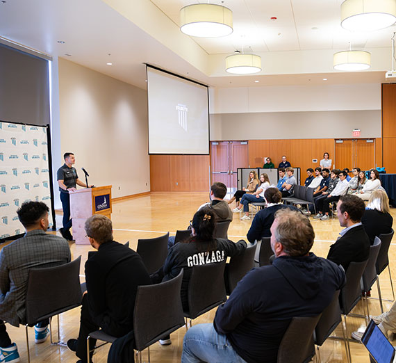 A man stands at a podium in front of a group of students