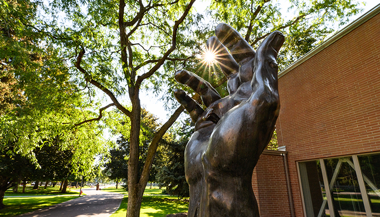 hand of christ sculpture backlit by sun
