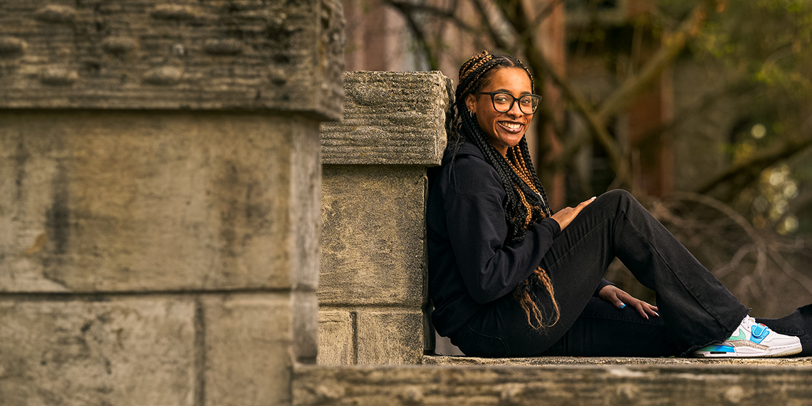 A woman sitting on the steps smiles at the camera