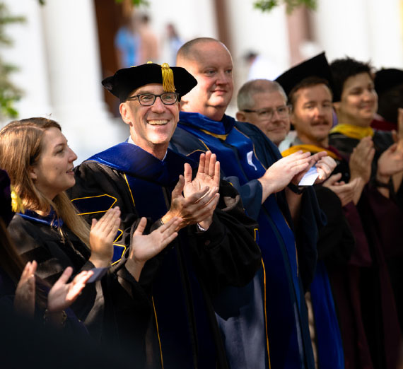 Group of faculty members laughing and clapping enthusiastically.