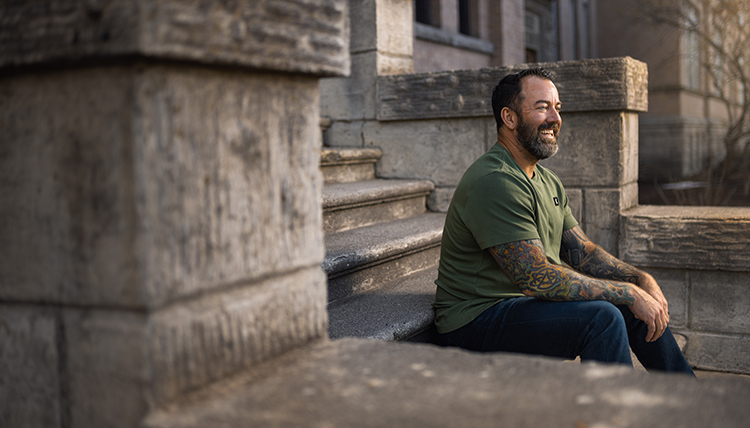 Dan Cummins sits on cement stairs outside Magnuson Theatre
