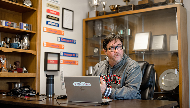 Debate Director Glen Frappier sits behind a laptop computer at his desk