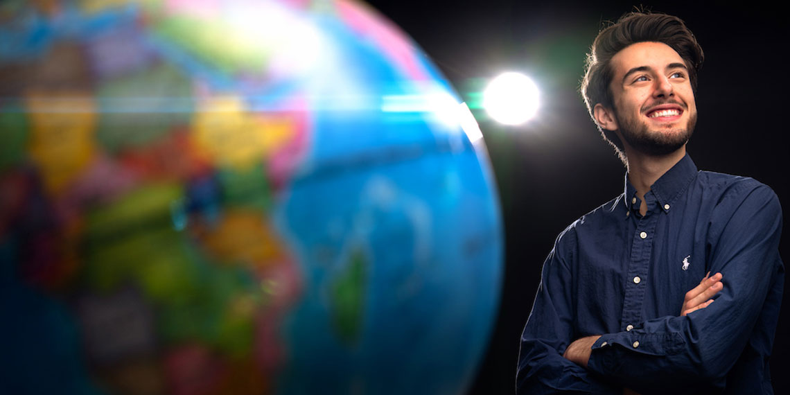 Gonzaga Senior Antoinne Herrbach, smiling next to close up of globe.
