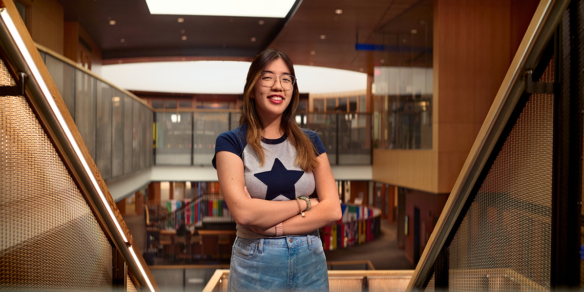 A woman in a t-shirt with a star on it stands with her arms crossed