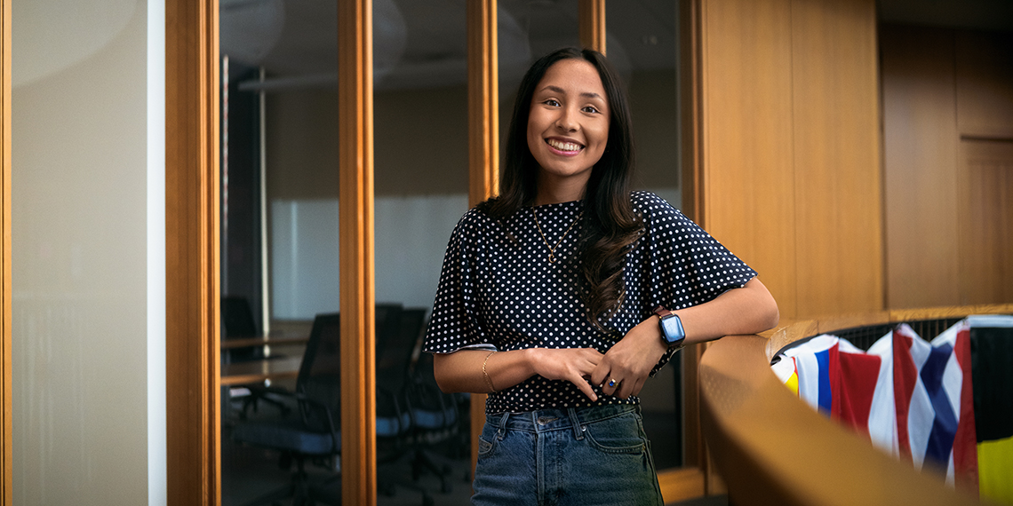 A woman stands leaning on a rail