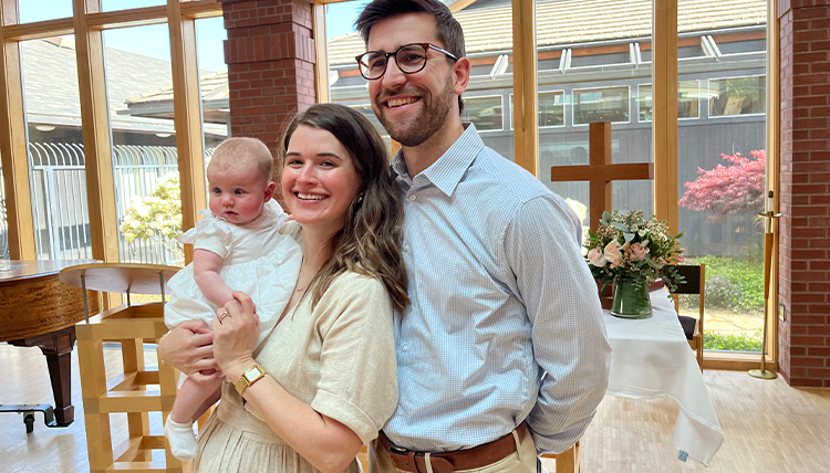 A couple smiles holding their baby.
