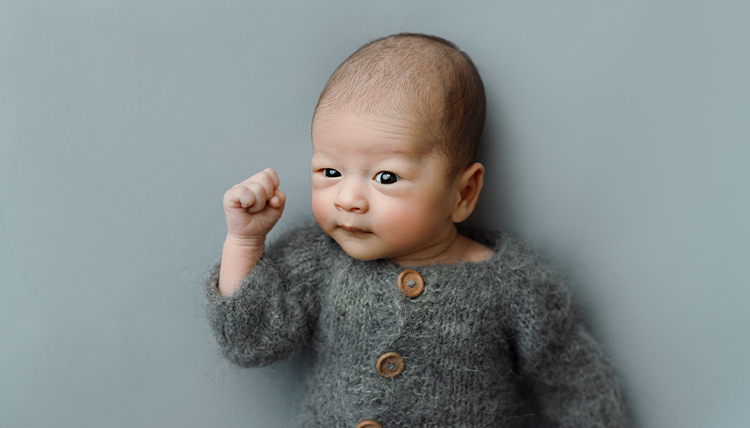 A baby in a little gray sweater.
