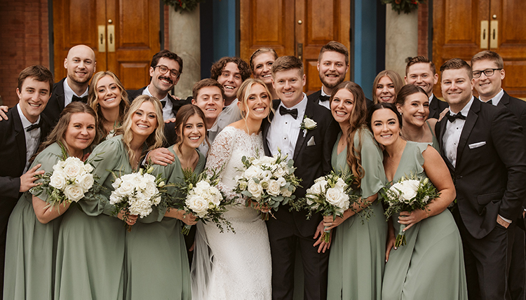 A wedding party smiles and poses together.