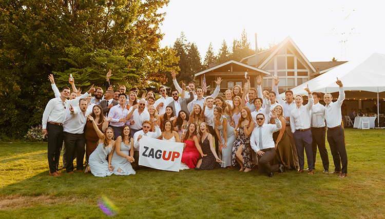 A group of people smile and pose holding a Gonzaga flag.