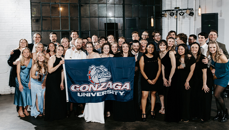 A group of people pose with a Gonzaga flag.