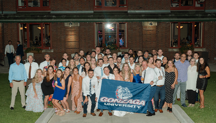 A group of people pose holding a Gonzaga flag.