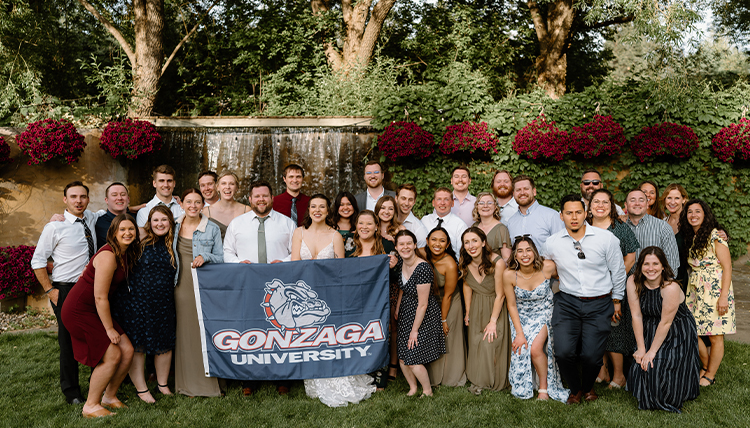 A group of people pose with a Gonzaga flag.