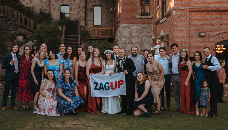 A group of people pose with a Gonzaga flag at a wedding.