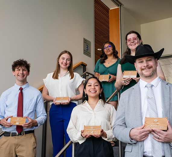give students holding awards standing on steps