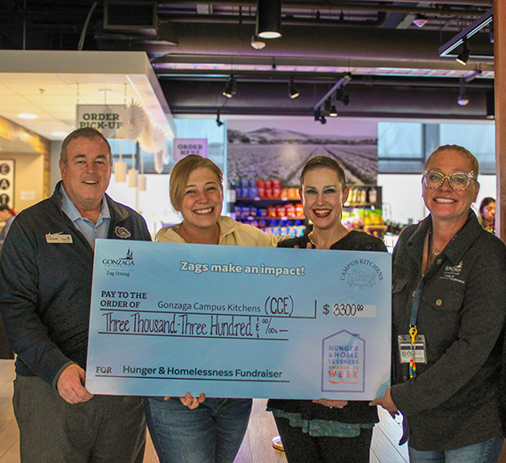 four people holding a giant check