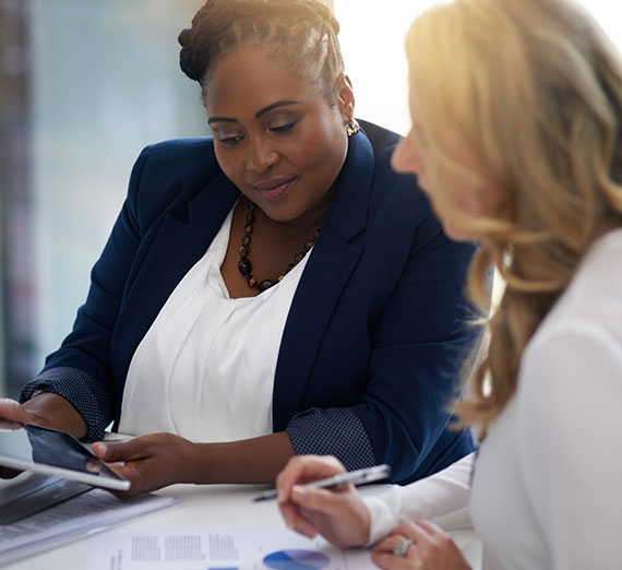 Two business women collaborating on tablets.