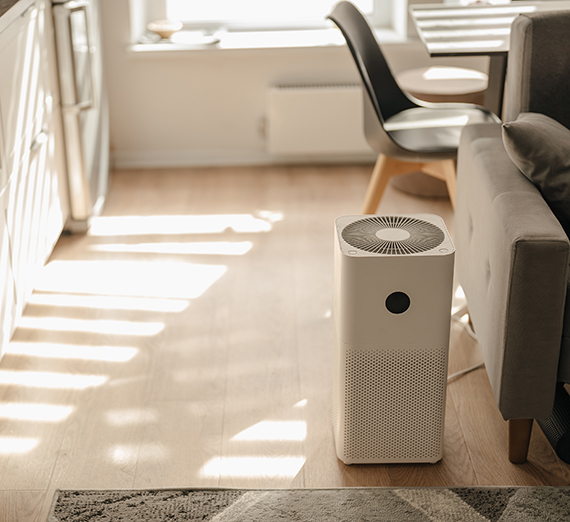 An air filter sits on the floor next to a couch