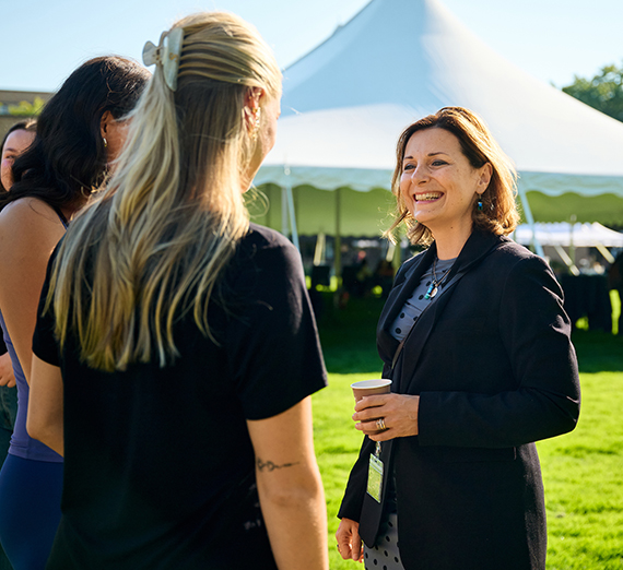 People chatting on lawn near white tent at outdoor event