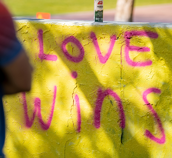 The words "Love Wins" painted in pink on a yellow wall