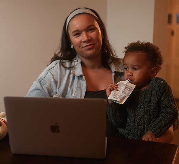 Jordy Jones poses with her laptop and her son on her lap.