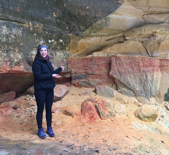 Dr. Madeleine Mathews stands in front of a rock formation.