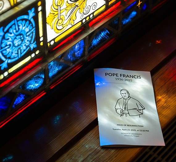A program from Gonzaga's Mass of Resurrection for Pope Francis, the first Jesuit pontiff, rests beside stained glass in the student chapel.