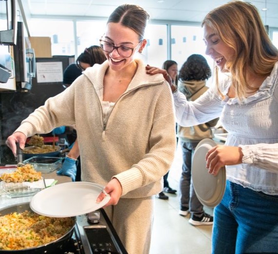 Two female students cooking rice in a kitchen.