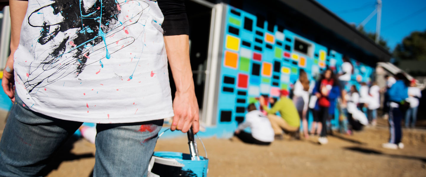 Students volunteering painting a mural 